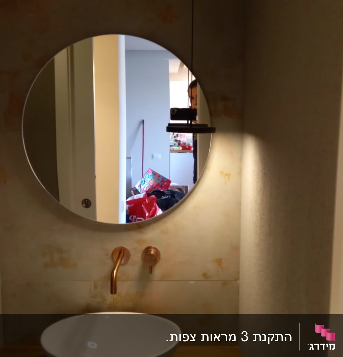 מראה עגולה תלויה על קיר בחדר אמבטיה